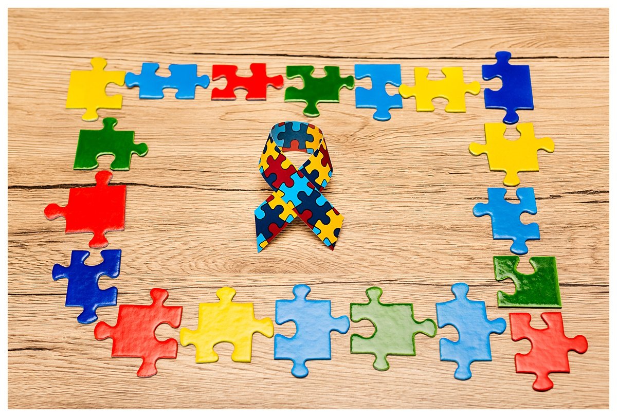 High angle view of awareness ribbon with colorful pieces of puzzle on wooden background, autism